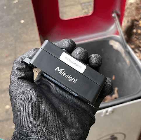 Milesight EM310-UDL ultrasonic sensor mounted inside a public waste bin